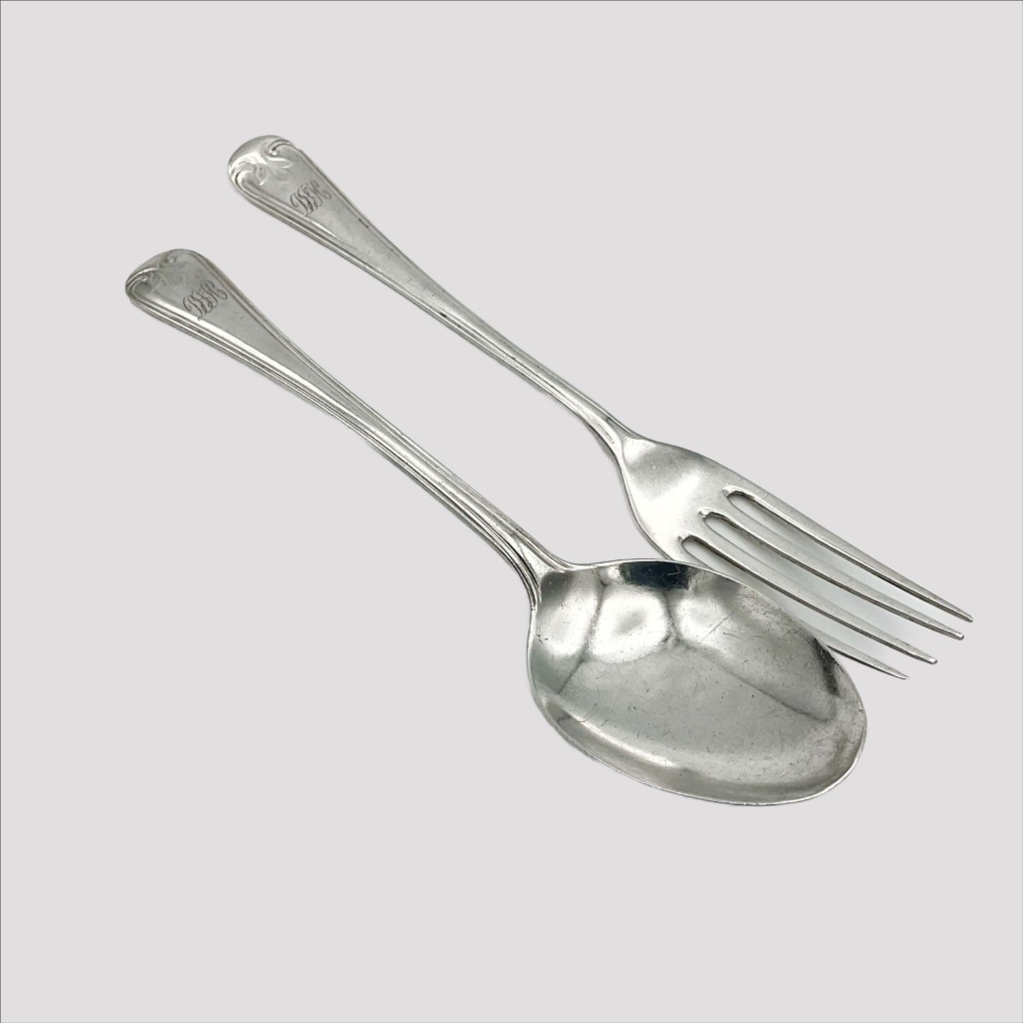 A matching silver spoon and fork sitting on a white background