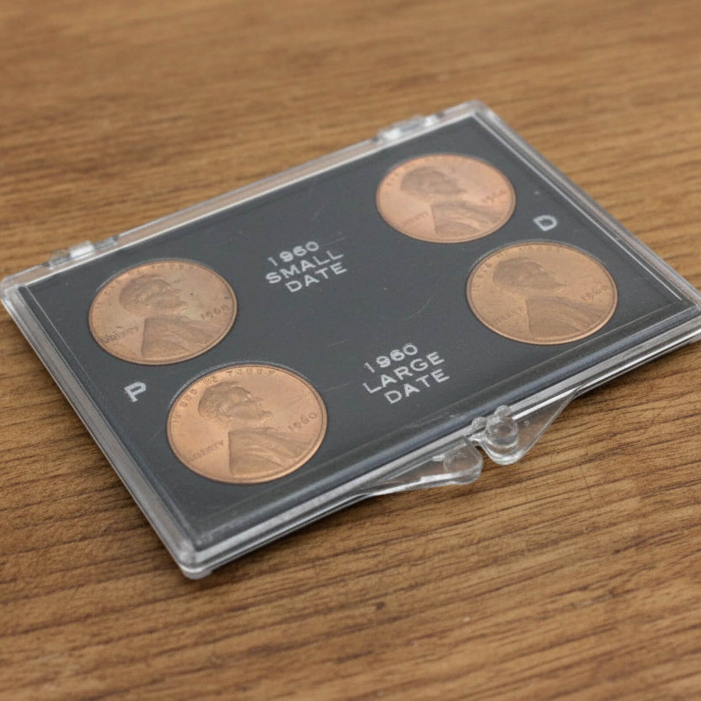 Set of four coins in a clear holder on a wooden surface