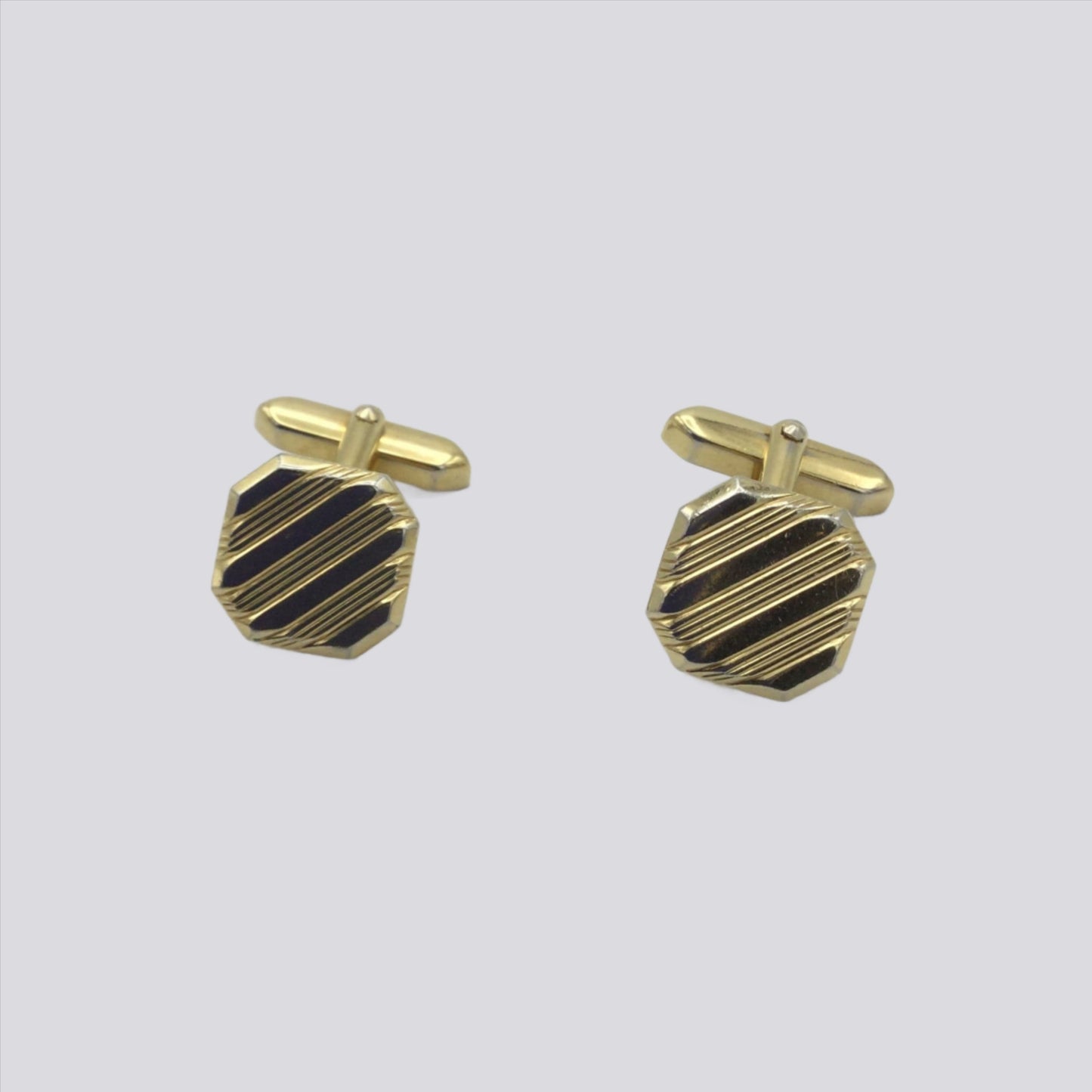 Gilded square cufflinks with a striped pattern on a white background