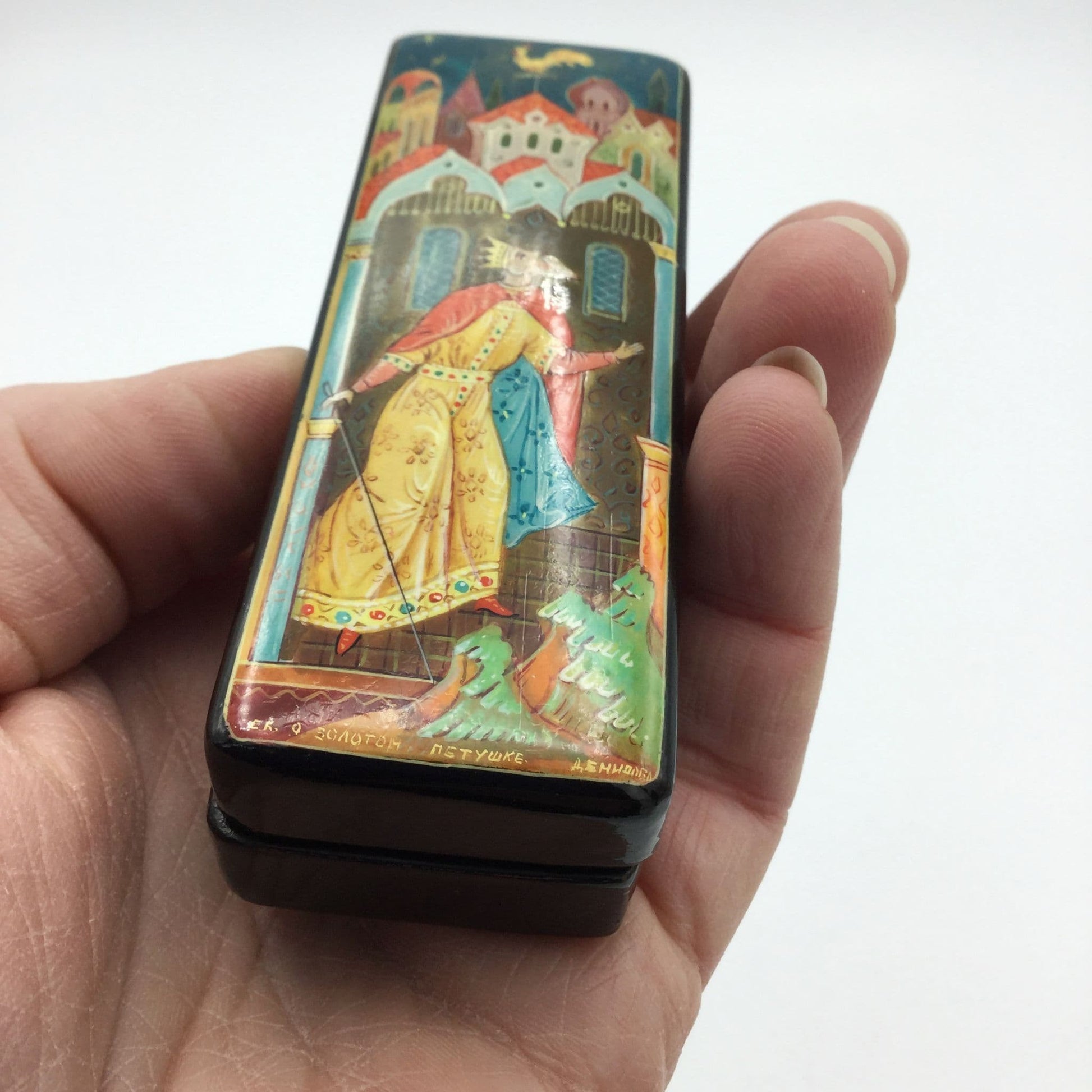 Black handpainted box with a colourful painting of a king looking at a cockerel above him held in a hand