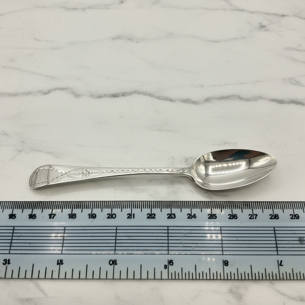 Silver spoon on a marble surface with a ruler for scale