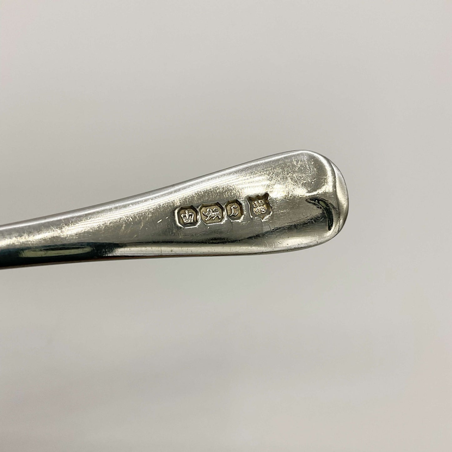 Antique silver teaspoon hallmarks on a handle with a white background