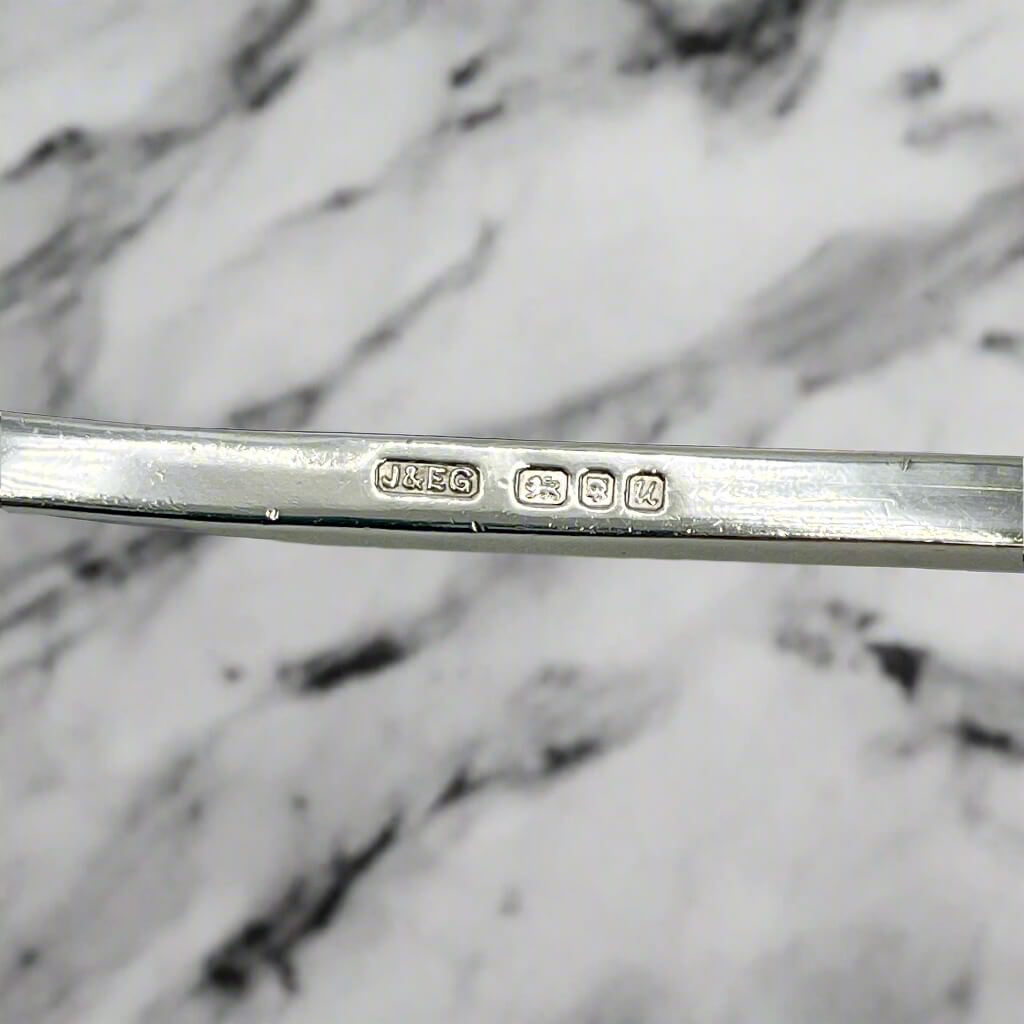 Silver spoon with engraved hallmarks on a marble background