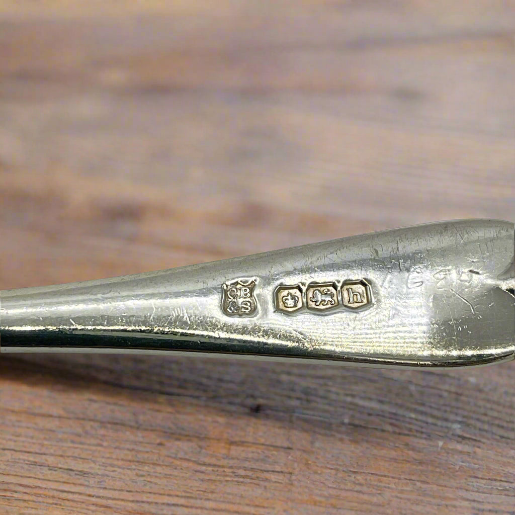 Silver spoon with visible hallmarks on a wooden surface