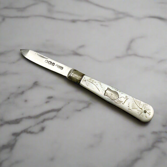 Silver fruit knife with a engraved mother of pearl handle on a white marble worktop