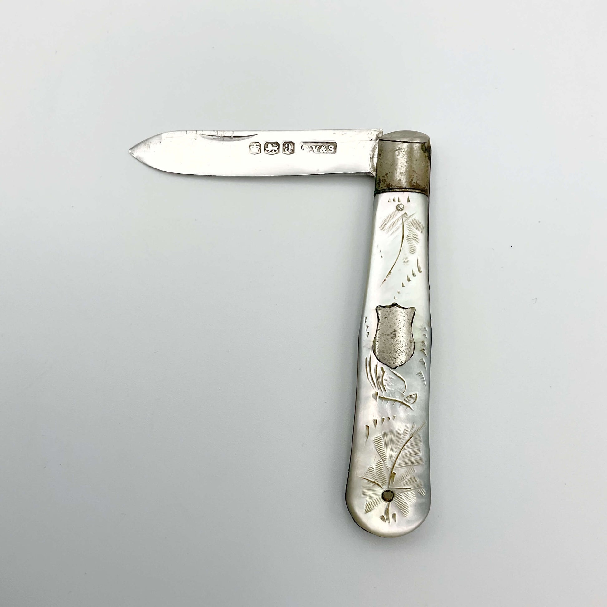 Silver fruit knife with a engraved mother of pearl handle on a white background
