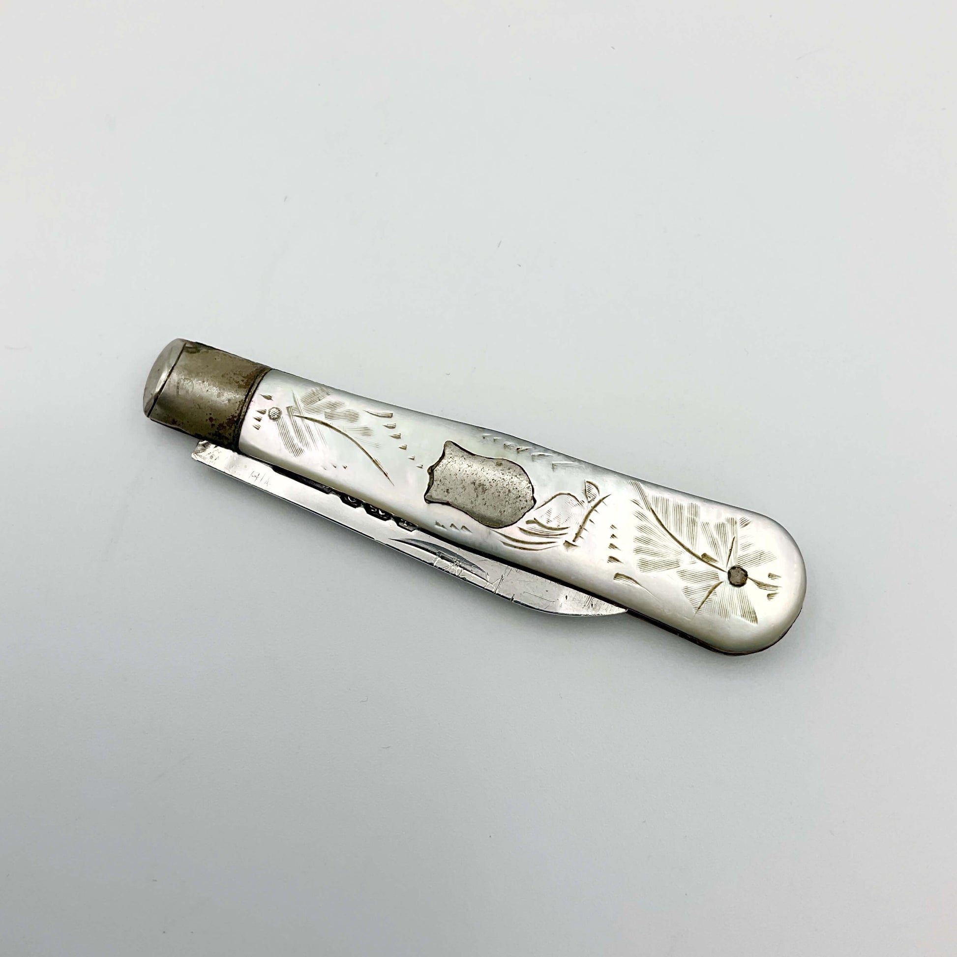 Silver fruit knife with a engraved mother of pearl handle with the blade folded away on a white background