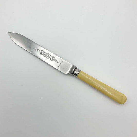 Antique cake knife with cream handle sitting on white background