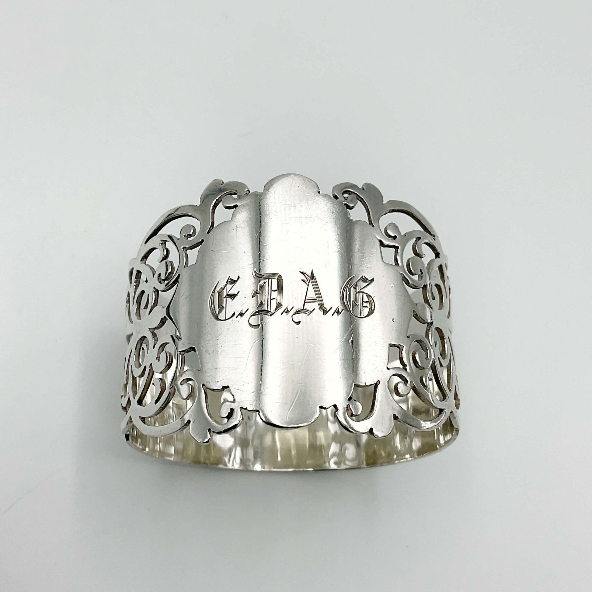 Shiny napkin ring with elaborate sides and EDAG in the centre on a plain background 