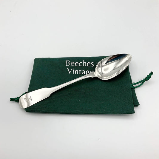 Silver dessert spoon on a green cotton gift bag