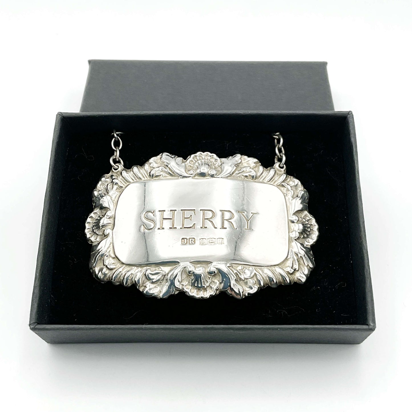 A shiny Sherry decanter label in a black presentation box on a white background.