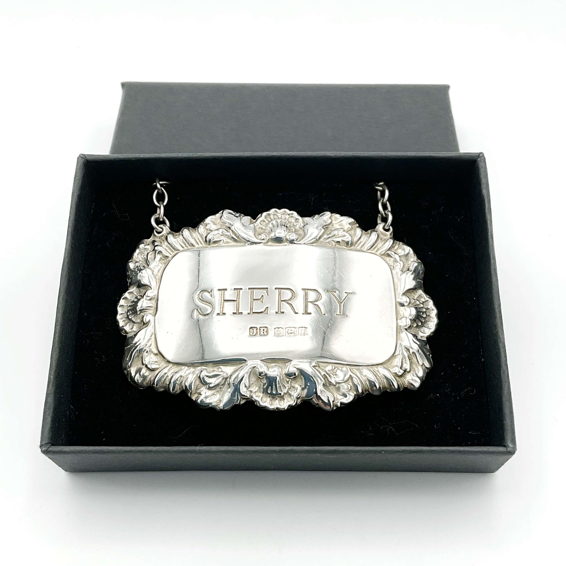 A shiny Sherry decanter label in a black presentation box on a white background.