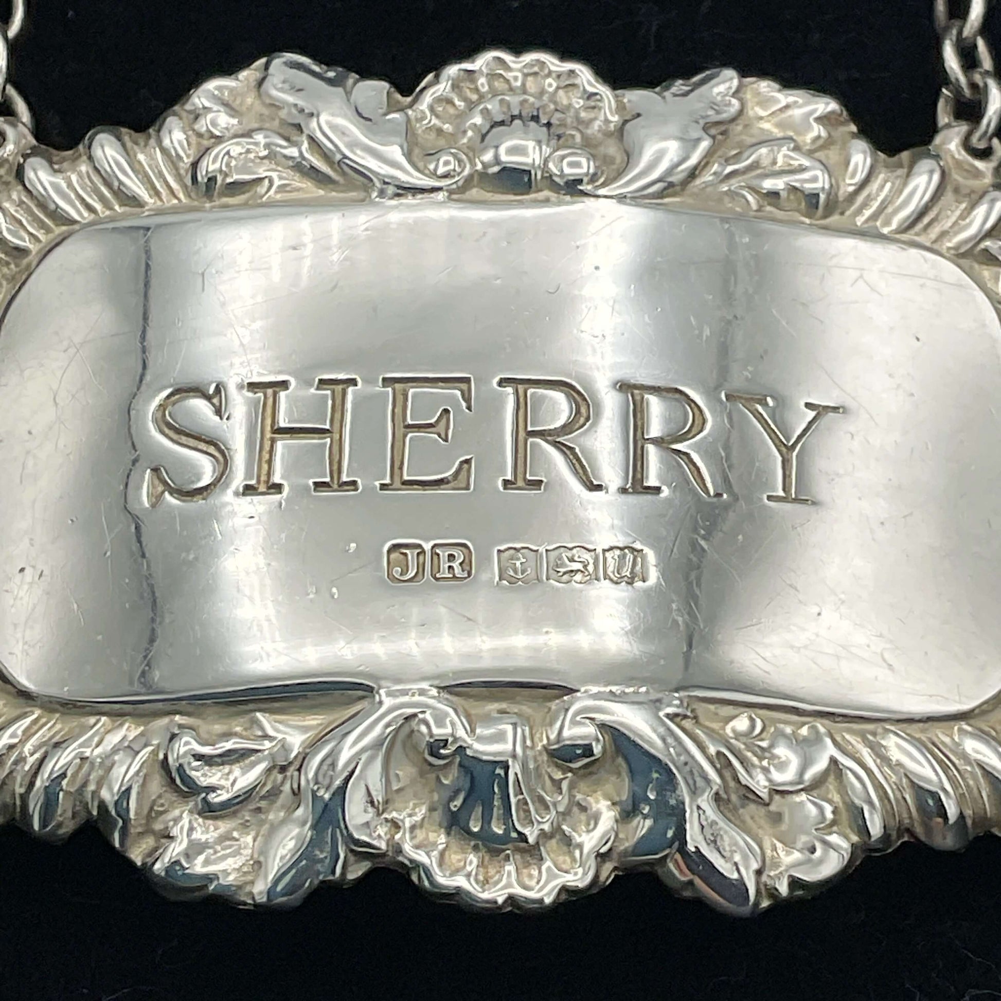 A shiny Sherry decanter label in front of a black presentation box.