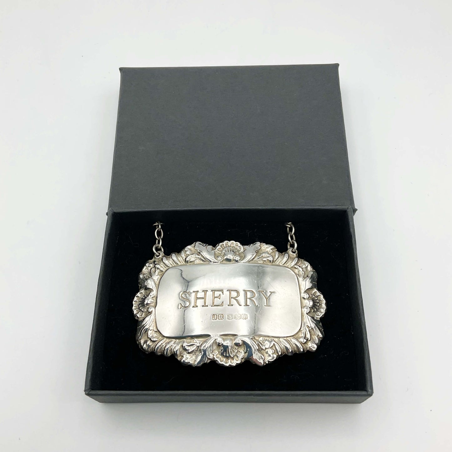 A shiny Sherry decanter label in a black presentation box on a white background.
