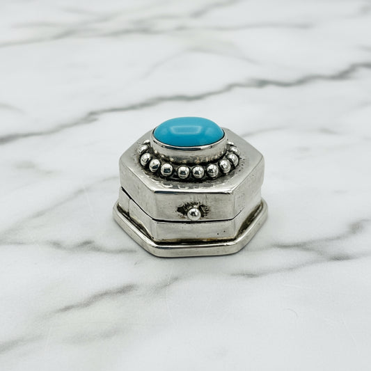 tiny pill box with turquoise lid on a marble surface