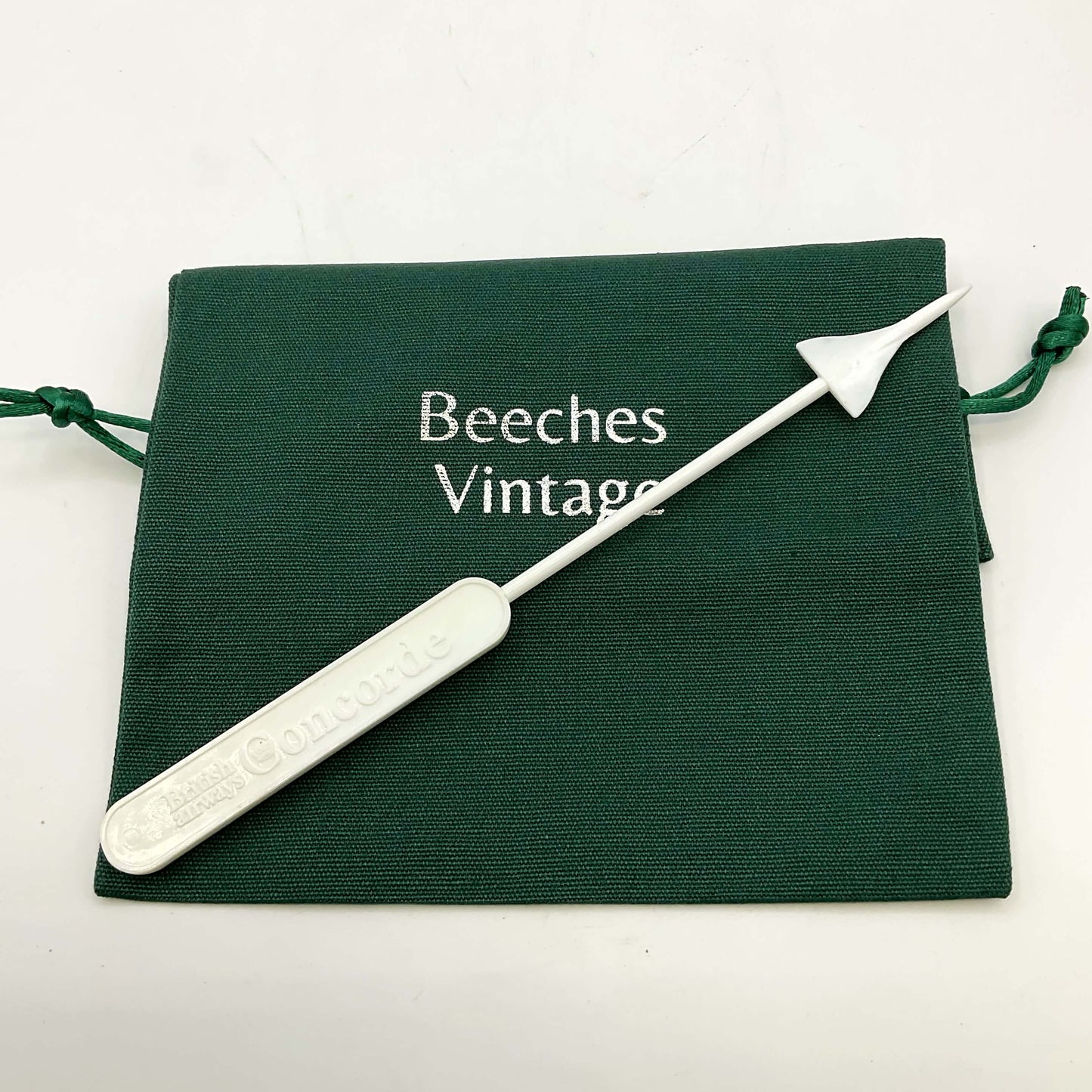 White Concorde Swizzle stick on a green gift bag and a white background