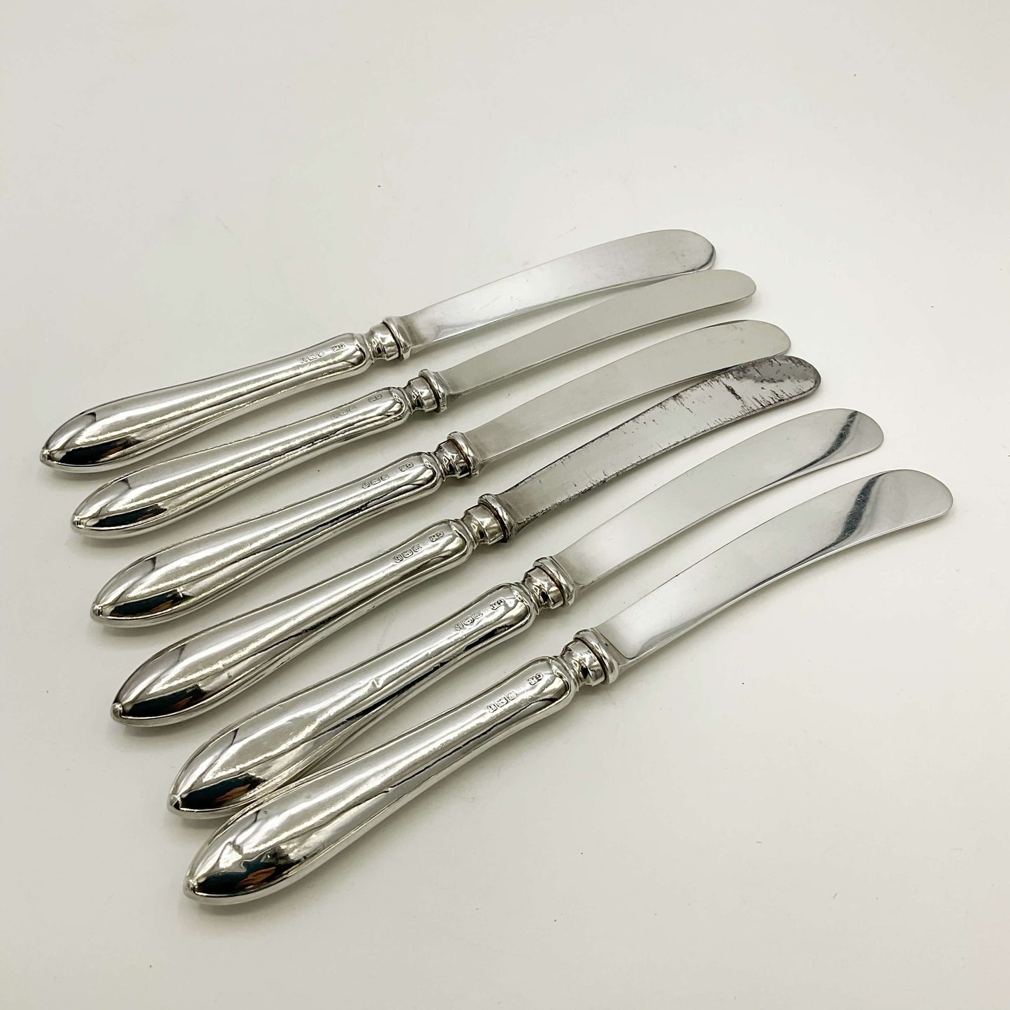Antique set of silver tea knives with a white background