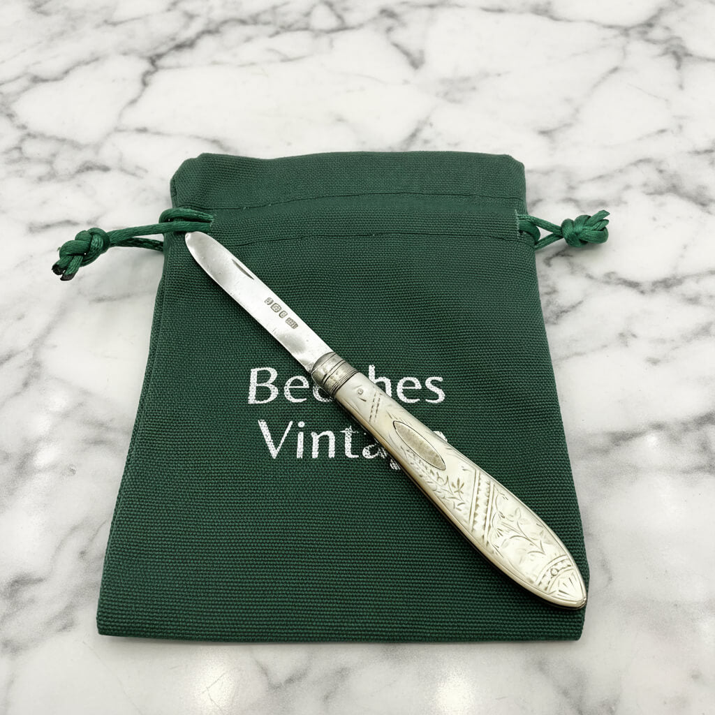 Decorative fruit knife on a green drawstring bag with 'Beeches Vintage' branding on a marble background