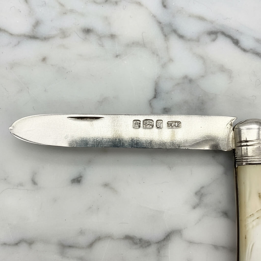 Silver knife with pearl handle on a marble surface