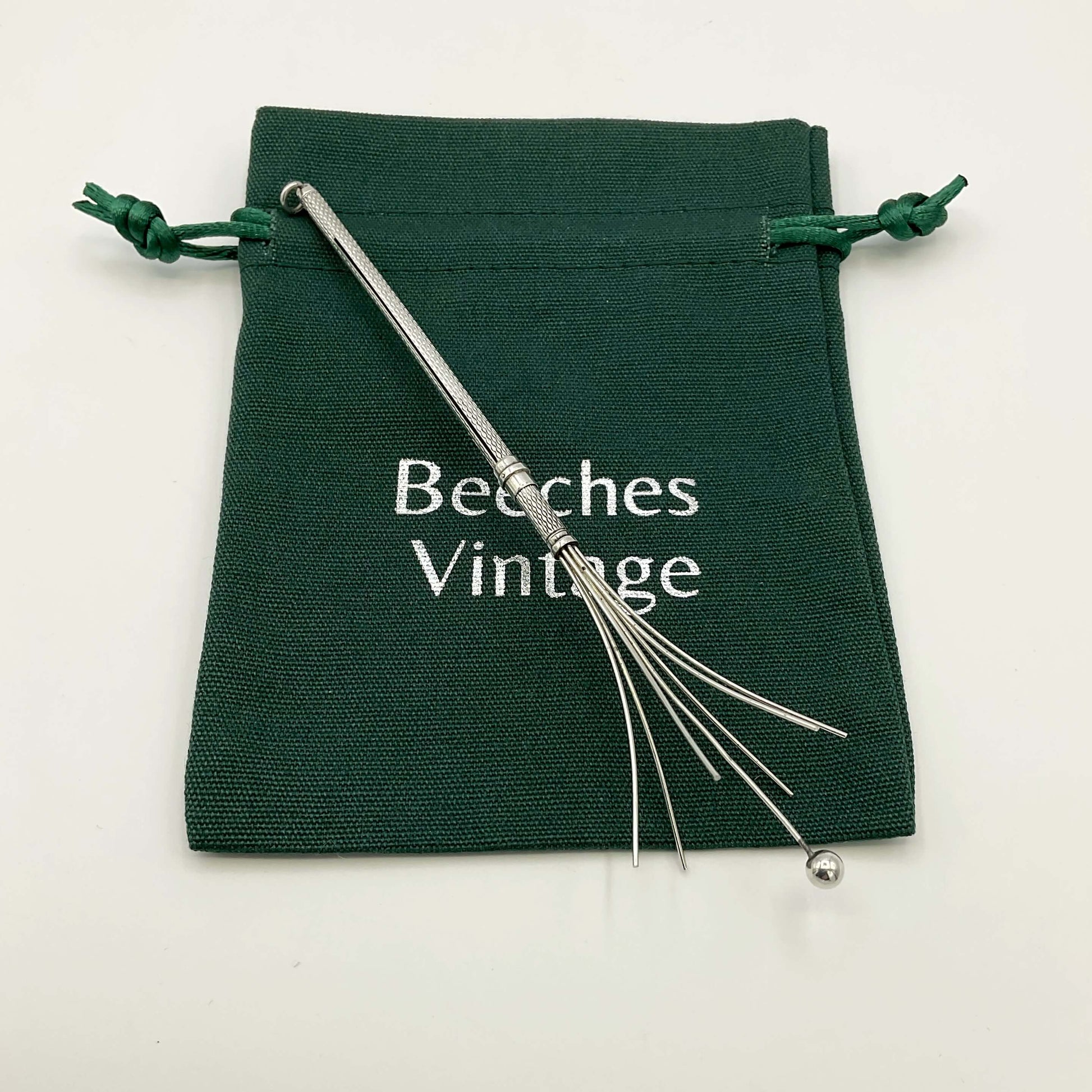 Silver whisk on a green bag with a white background