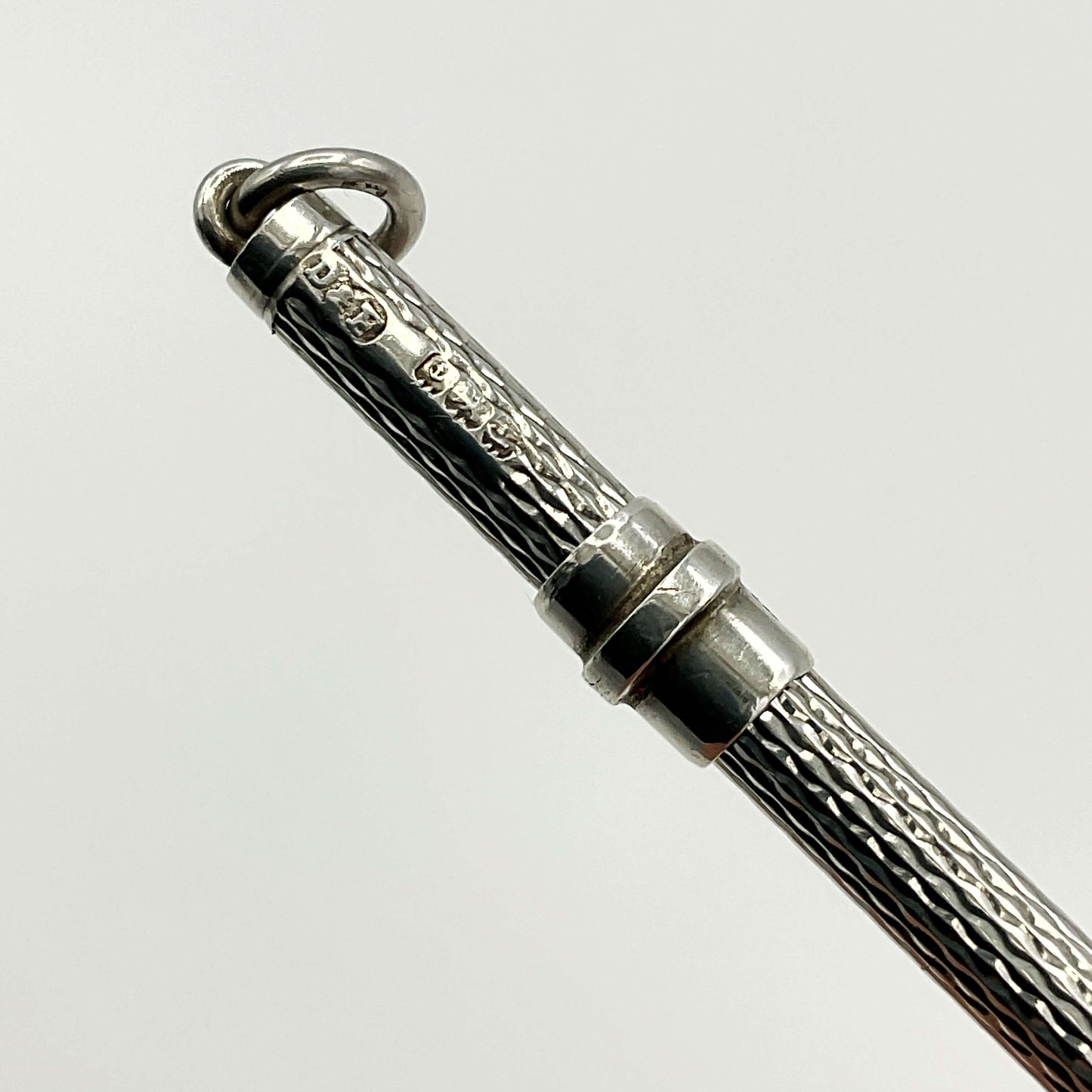Hallmarks on a silver cocktail whisk with a white background