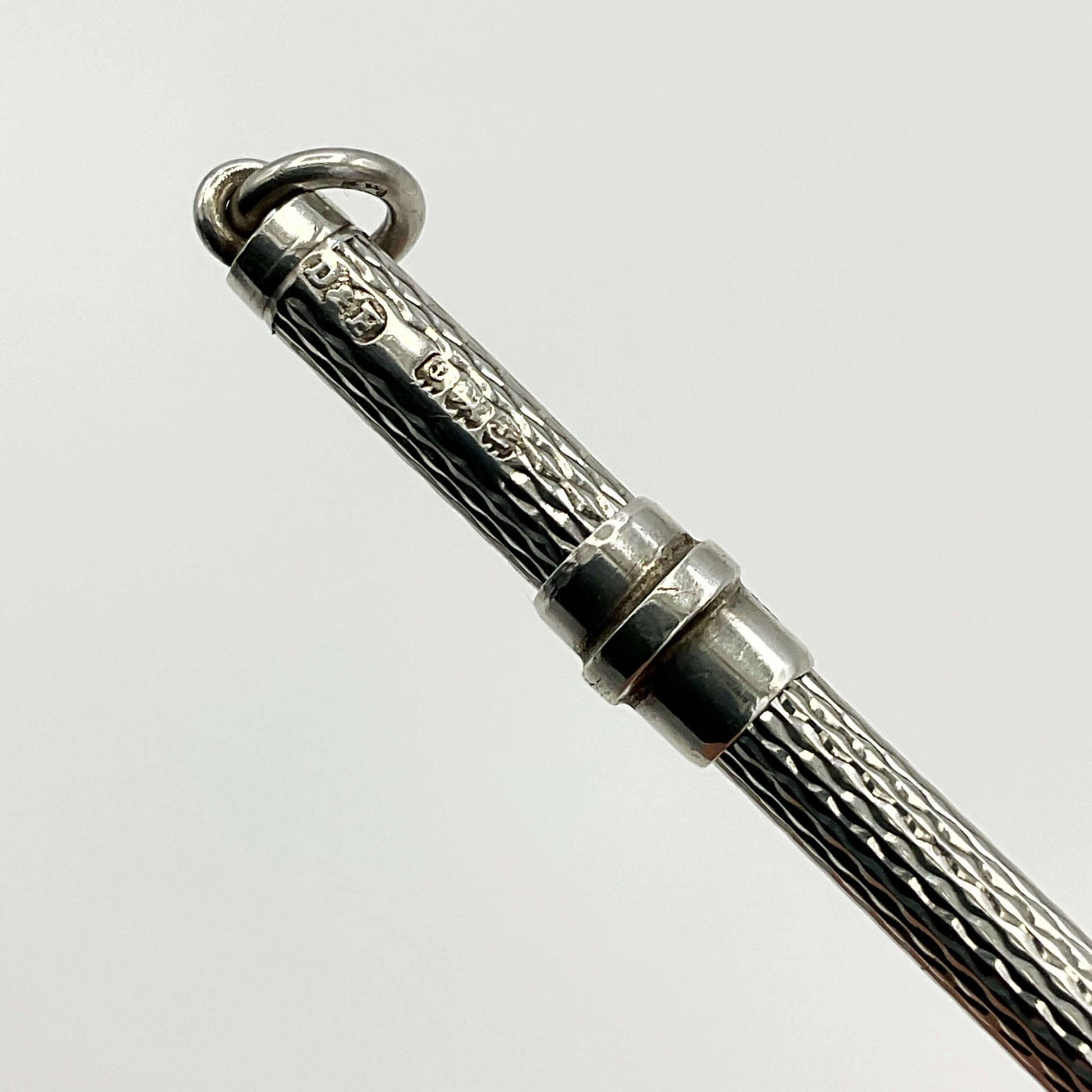 Hallmarks on a silver cocktail whisk with a white background