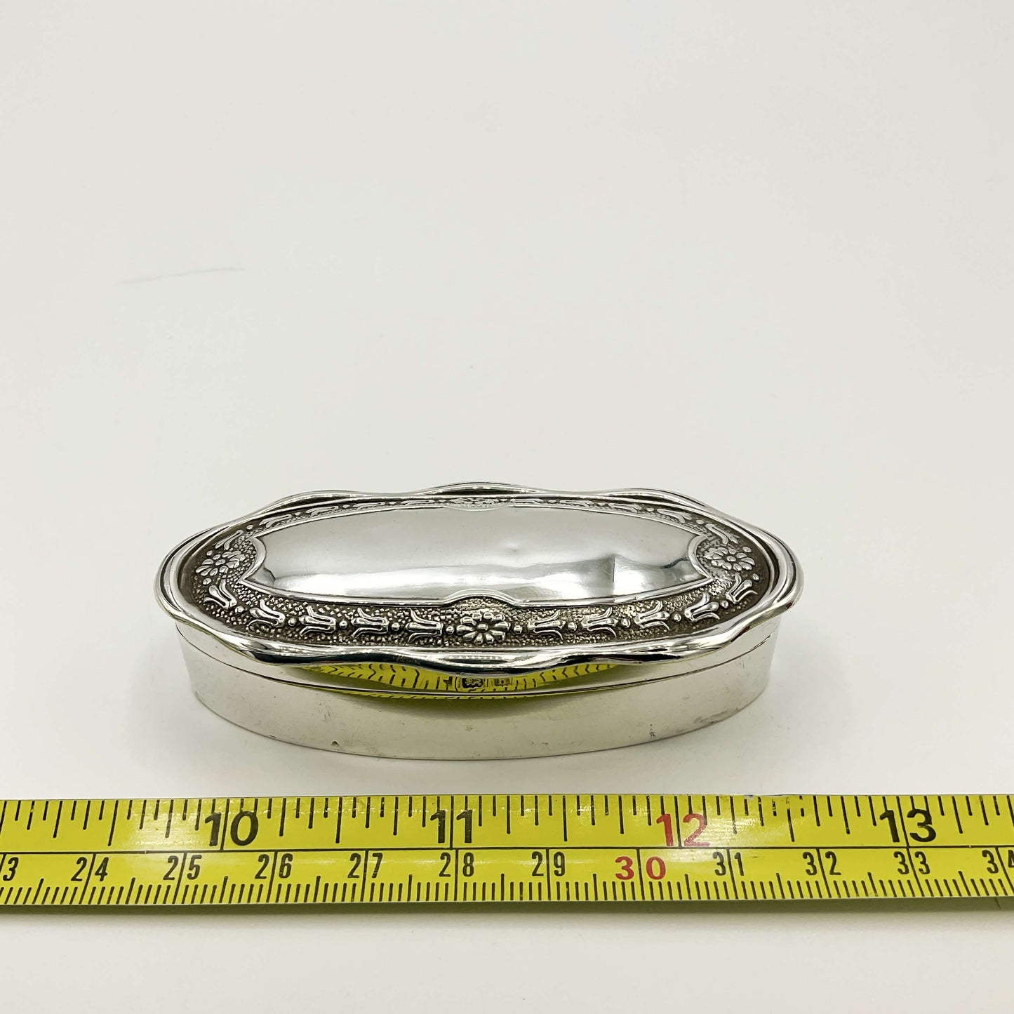 Small Antique silver jewellery box next to a tape measure on a white background showing the width as 3 inches