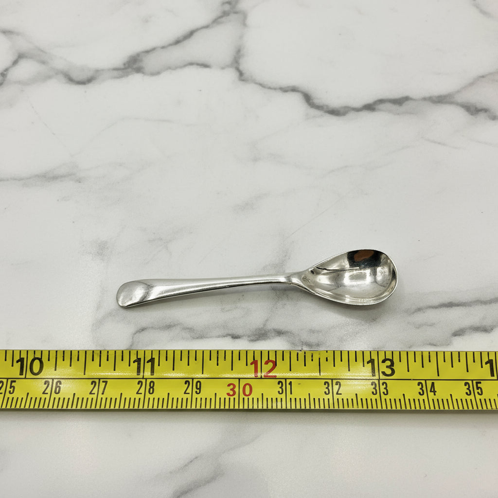 Silver spoon next to a measuring tape on a marble worktop