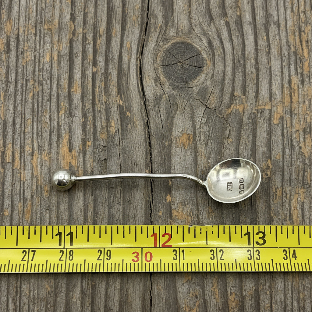Silver spoon with measurement tape showing its length on a wood background