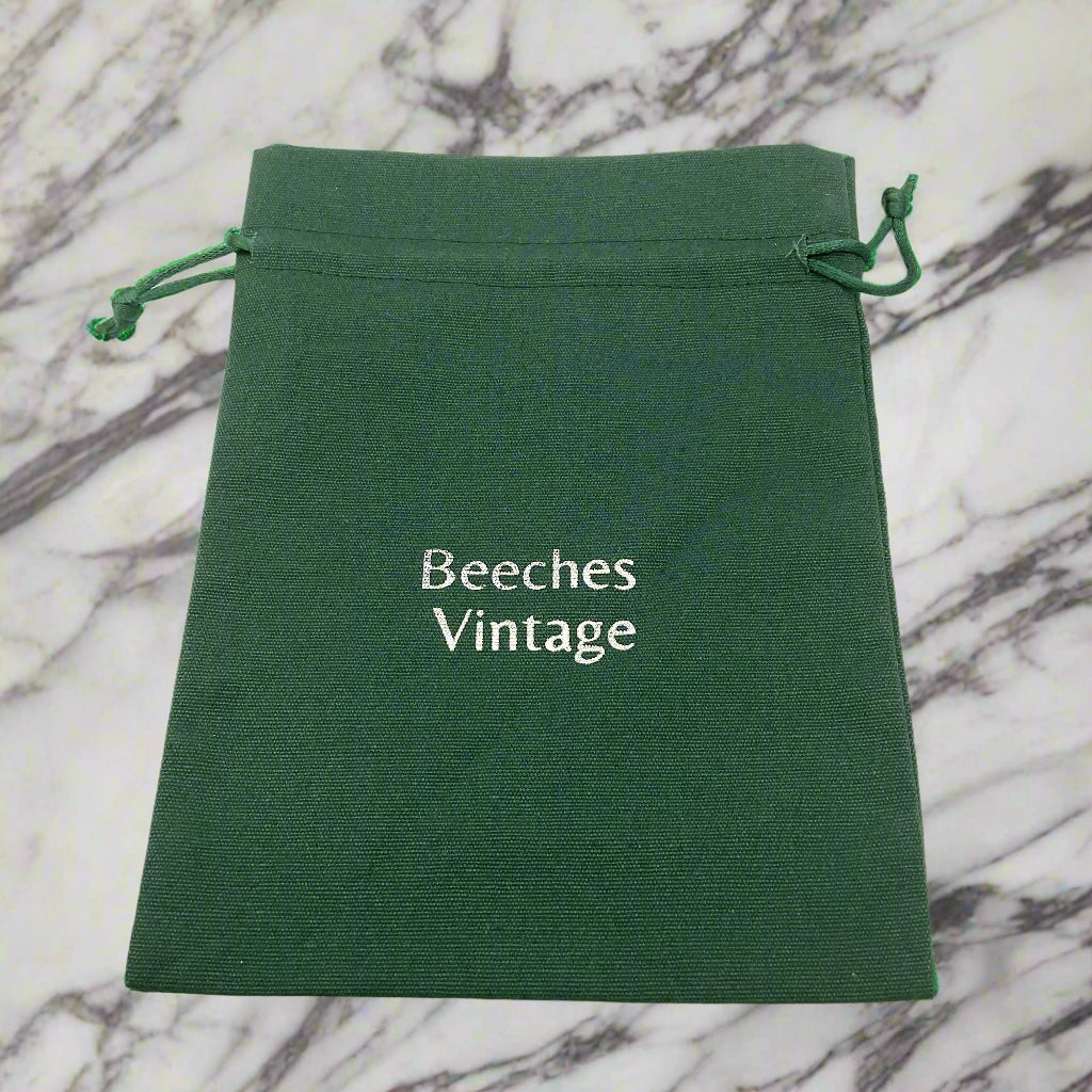 Green drawstring pouch with 'Beeches Vintage' text on a marble worktop