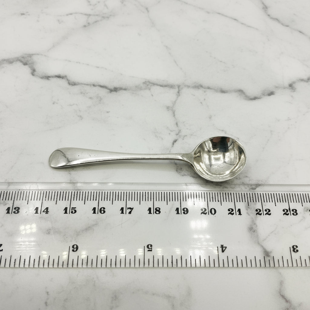 Silver spoon next to a ruler on a marble background