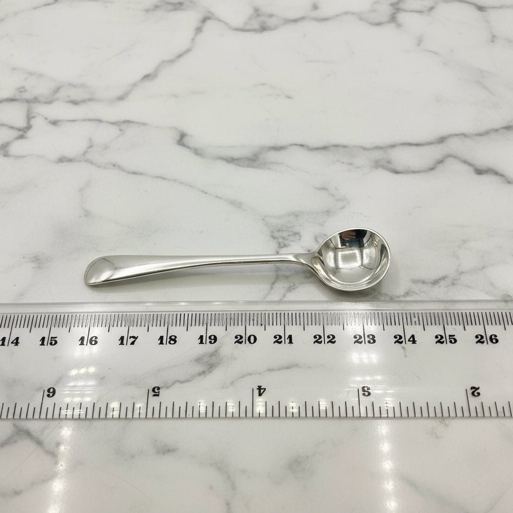 Silver spoon next to a ruler on a marble background
