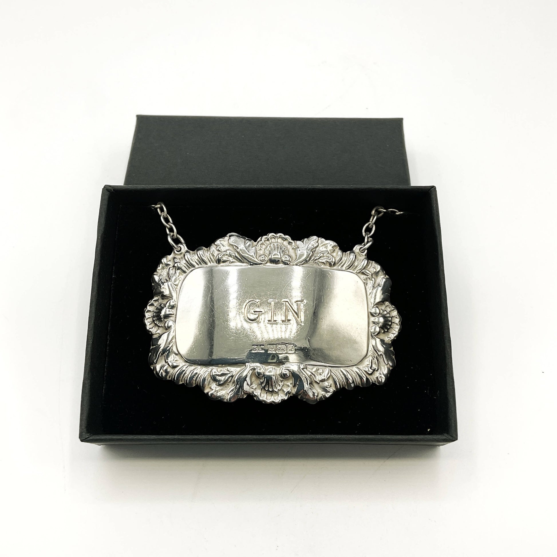 Silver label with GIN engraving in a black box on a white background