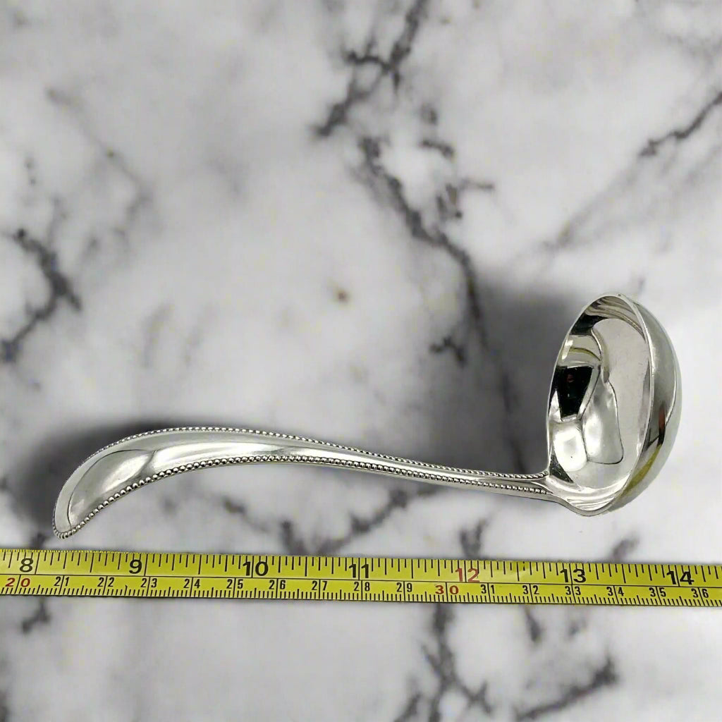 silver ladle next to tape measure on a marble surface