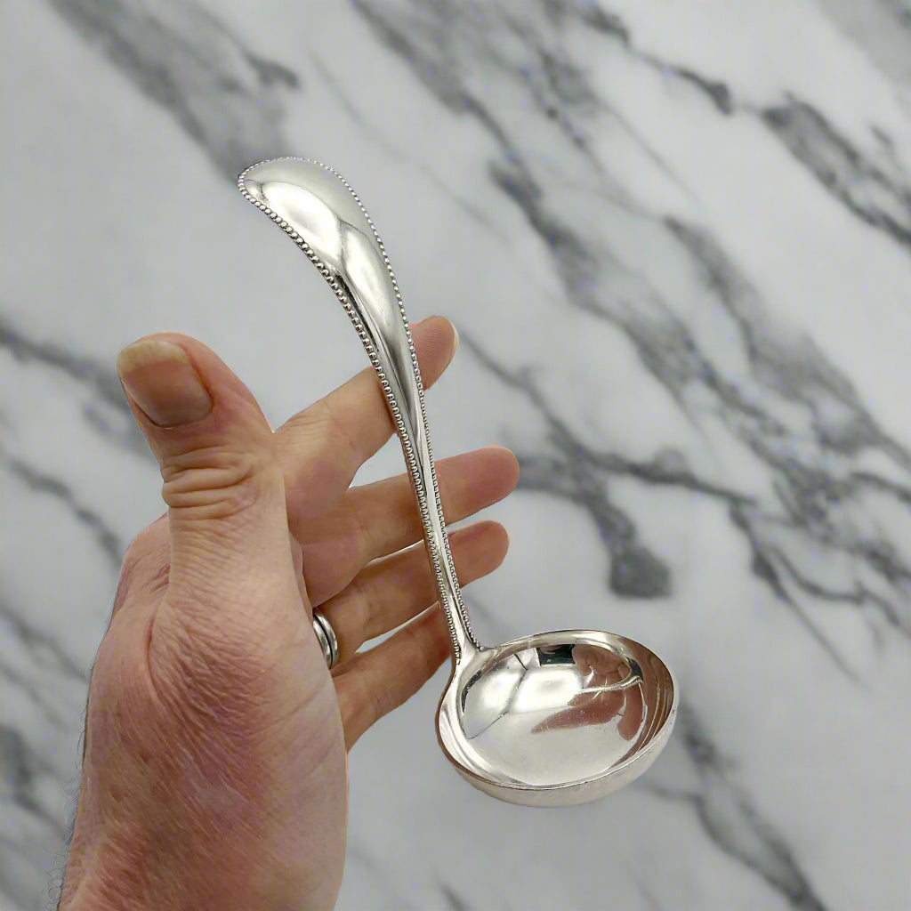 silver ladle held in a hand with a marble background
