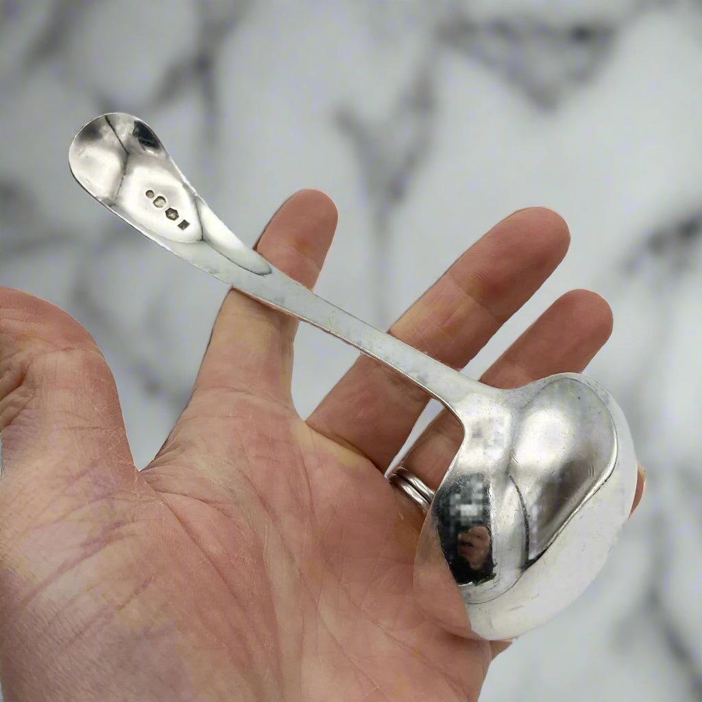 back of ladle held in a hand with a marble background