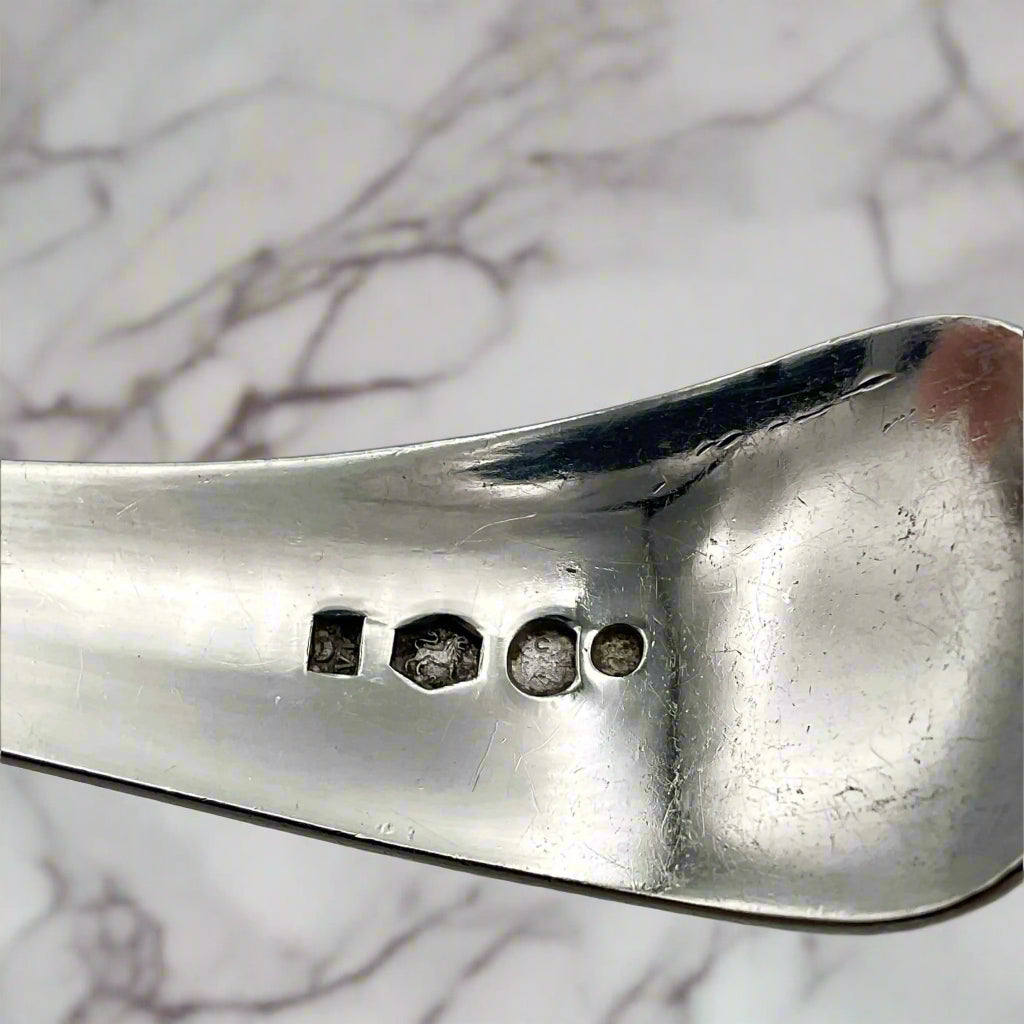 Dutch hallmarks on the back of a ladle with a marble backround