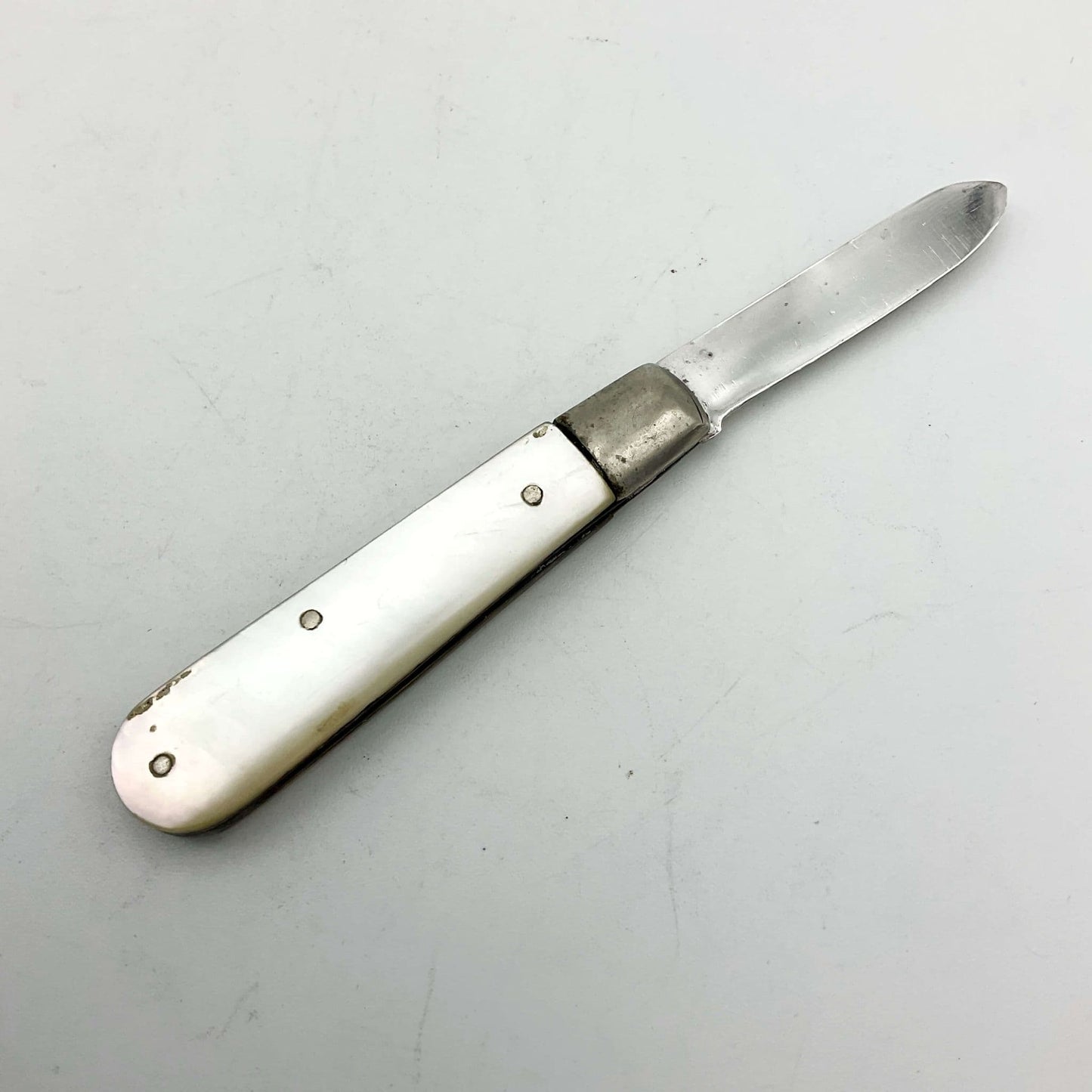 Silver fruit knife with a mother of pearl handle on a white background