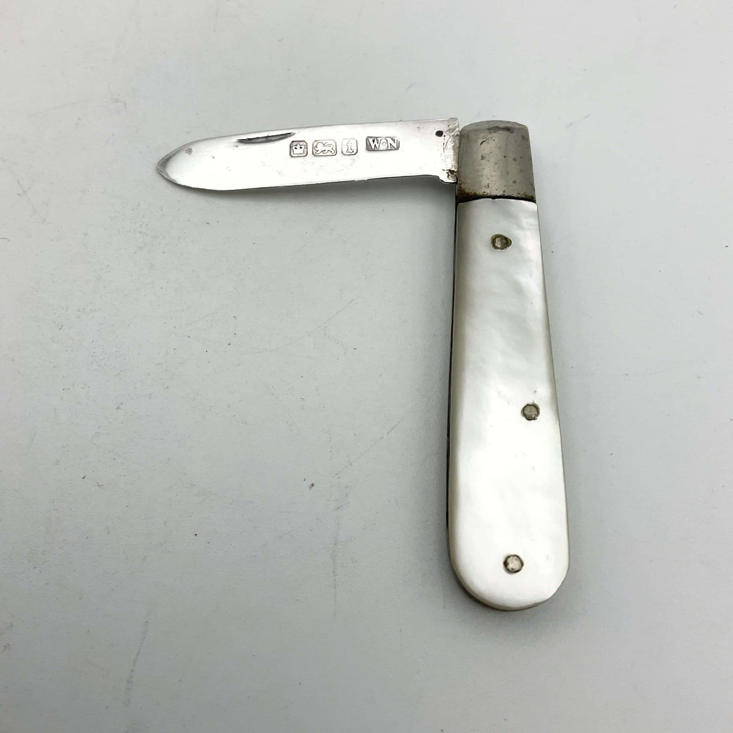 Silver fruit knife with a mother of pearl handle on a white background