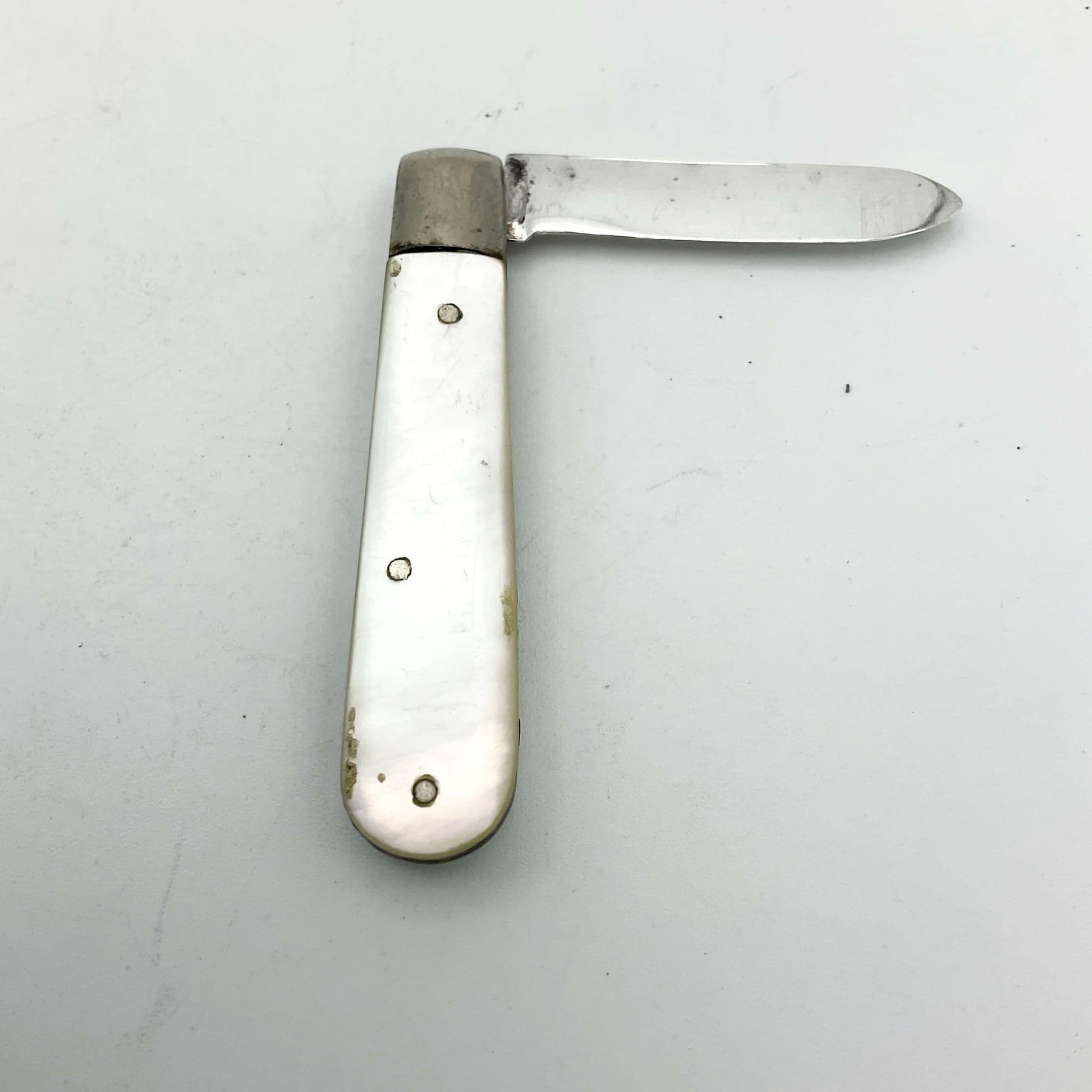 Silver fruit knife with a mother of pearl handle on a white background