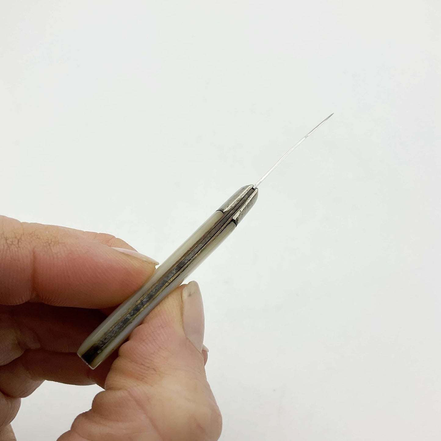 Top view of Silver fruit knife with a mother of pearl handle held in a hand.
