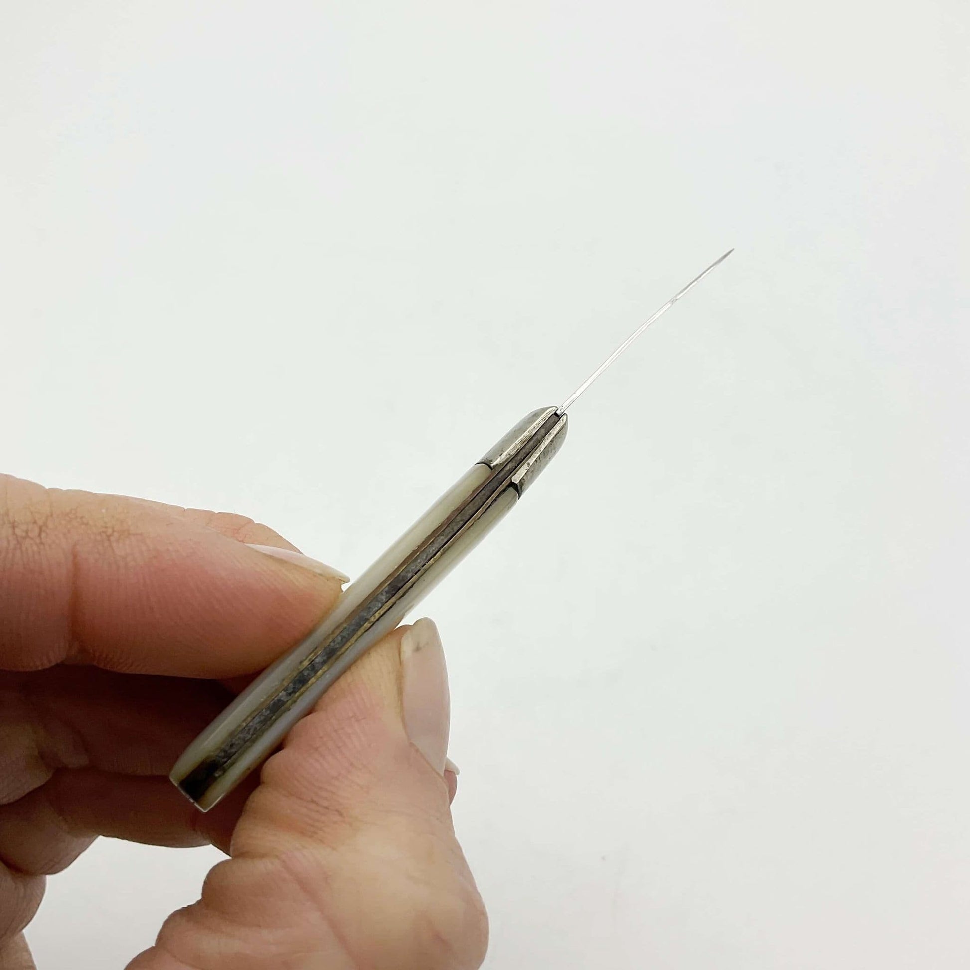 Top view of Silver fruit knife with a mother of pearl handle held in a hand.
