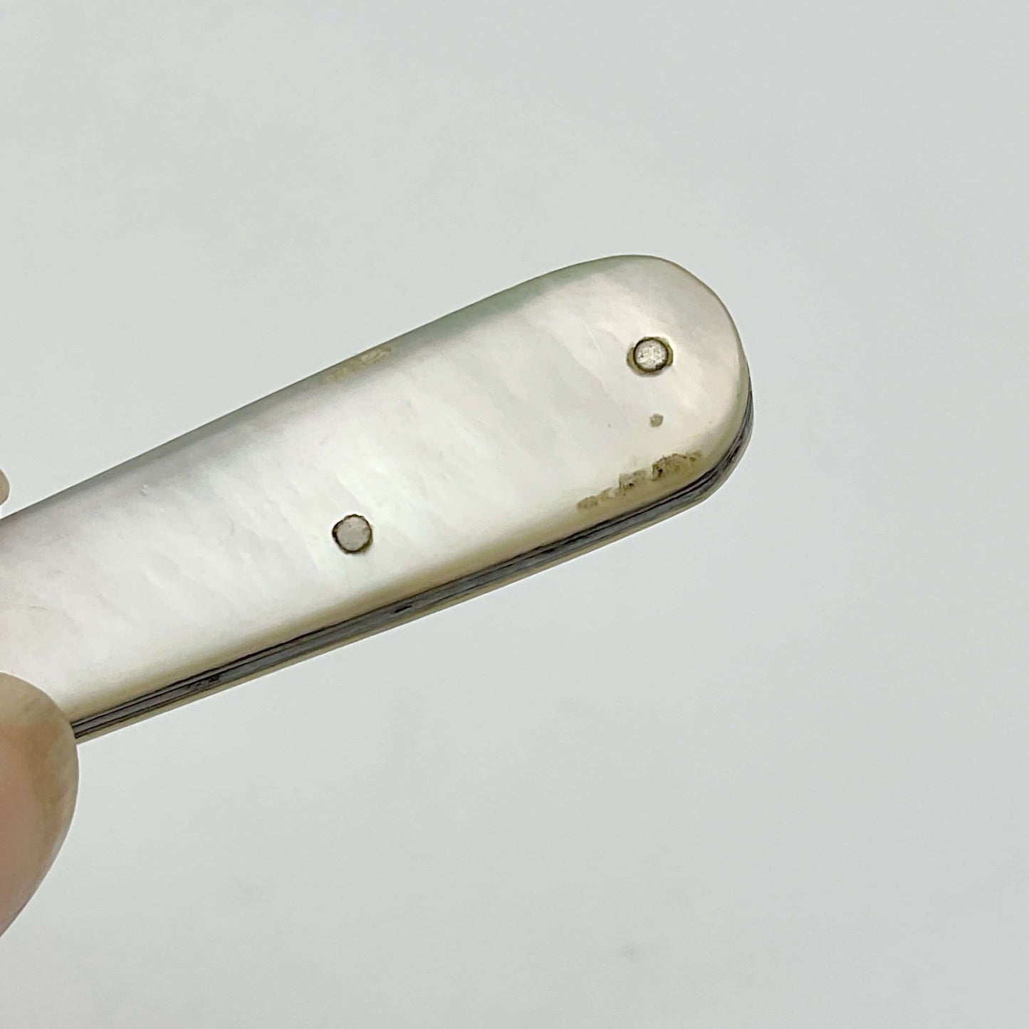 Mother of pearl handle showing a few marks at the end on a white background