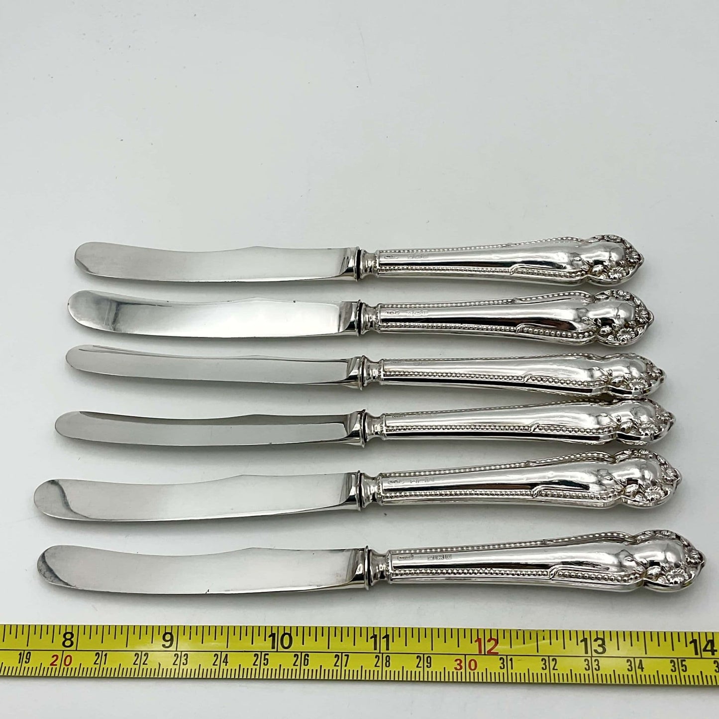 Set of six side knives next to a tape measure 