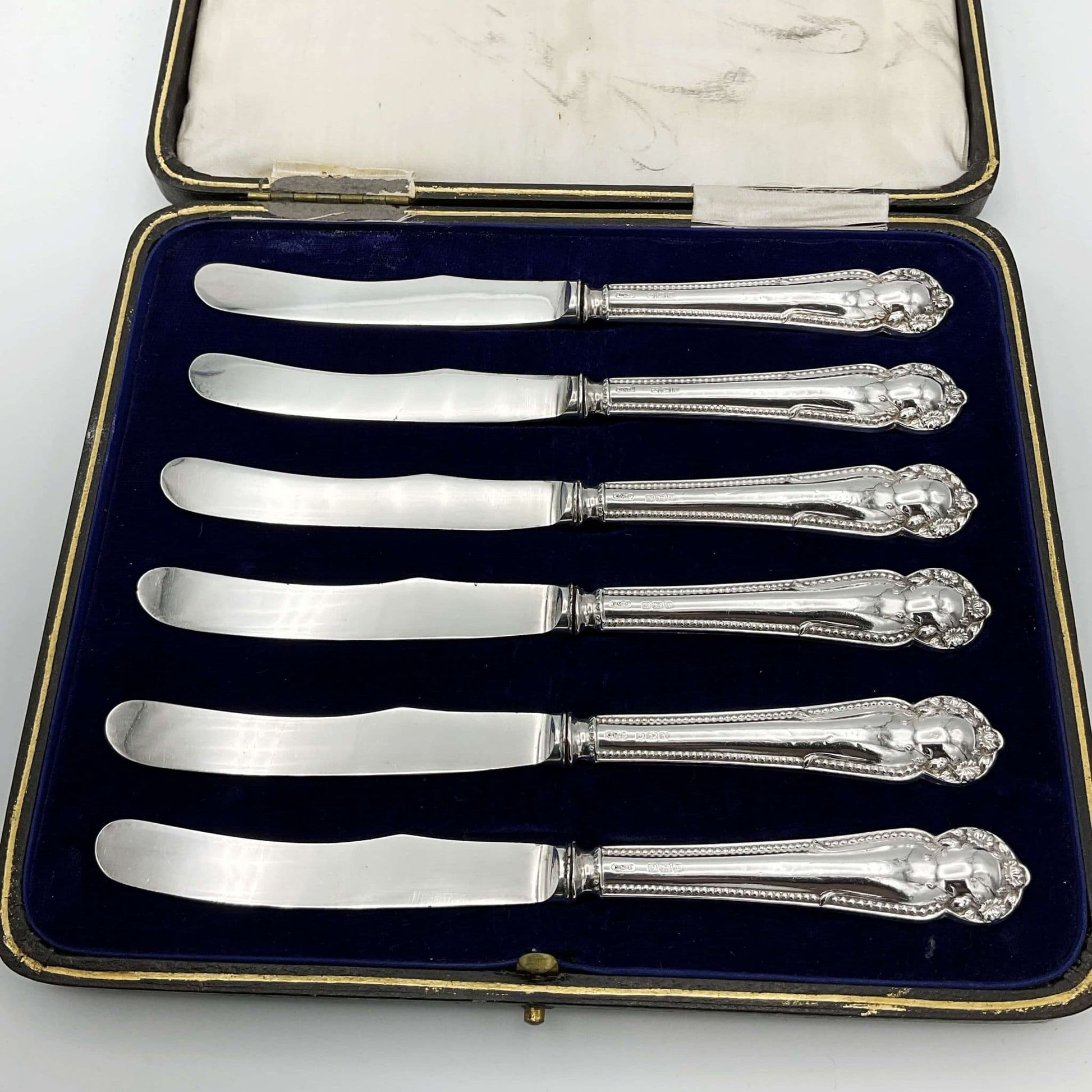  Boxed set of antique silver tea knives on a plain background