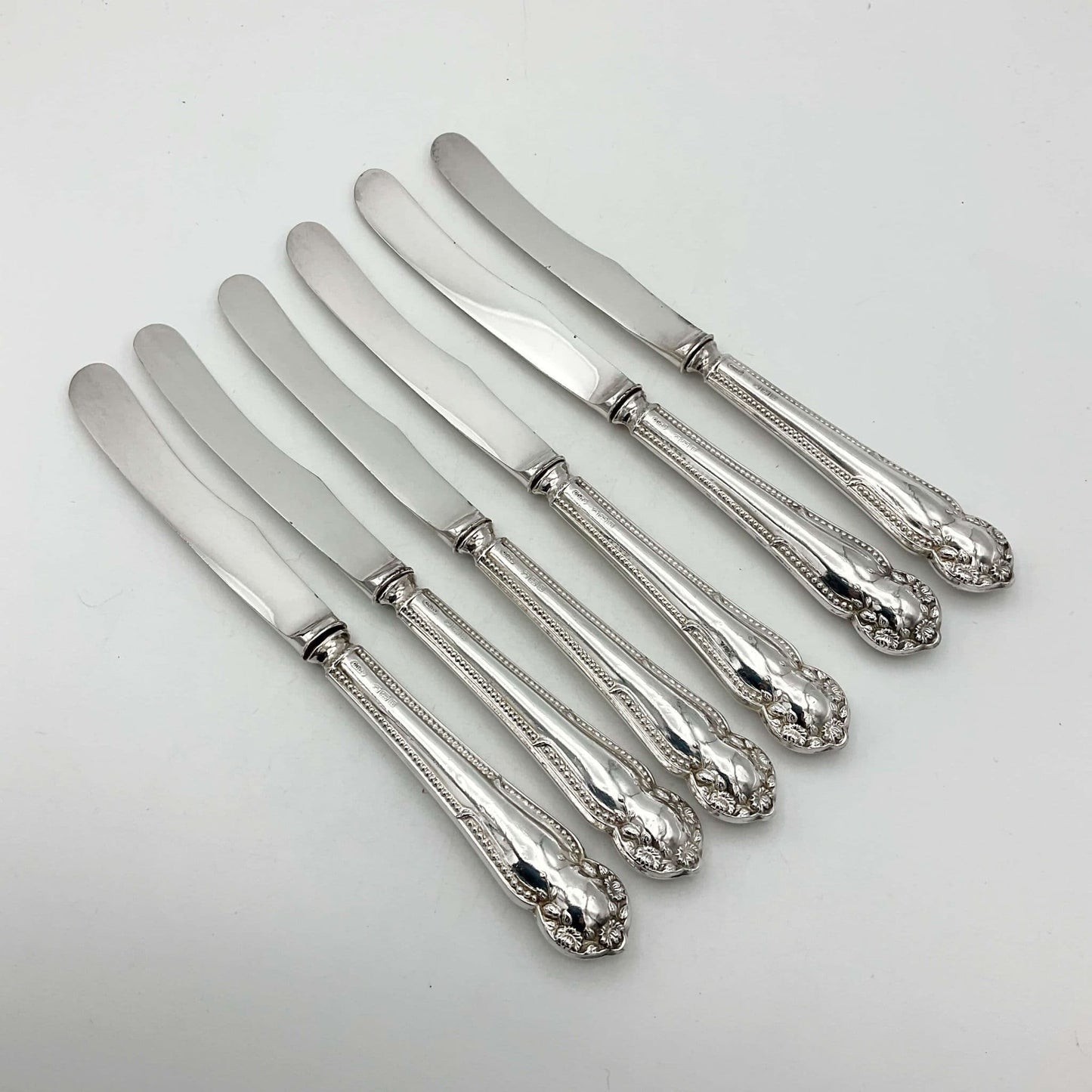  Six antique silver tea knives on a plain background