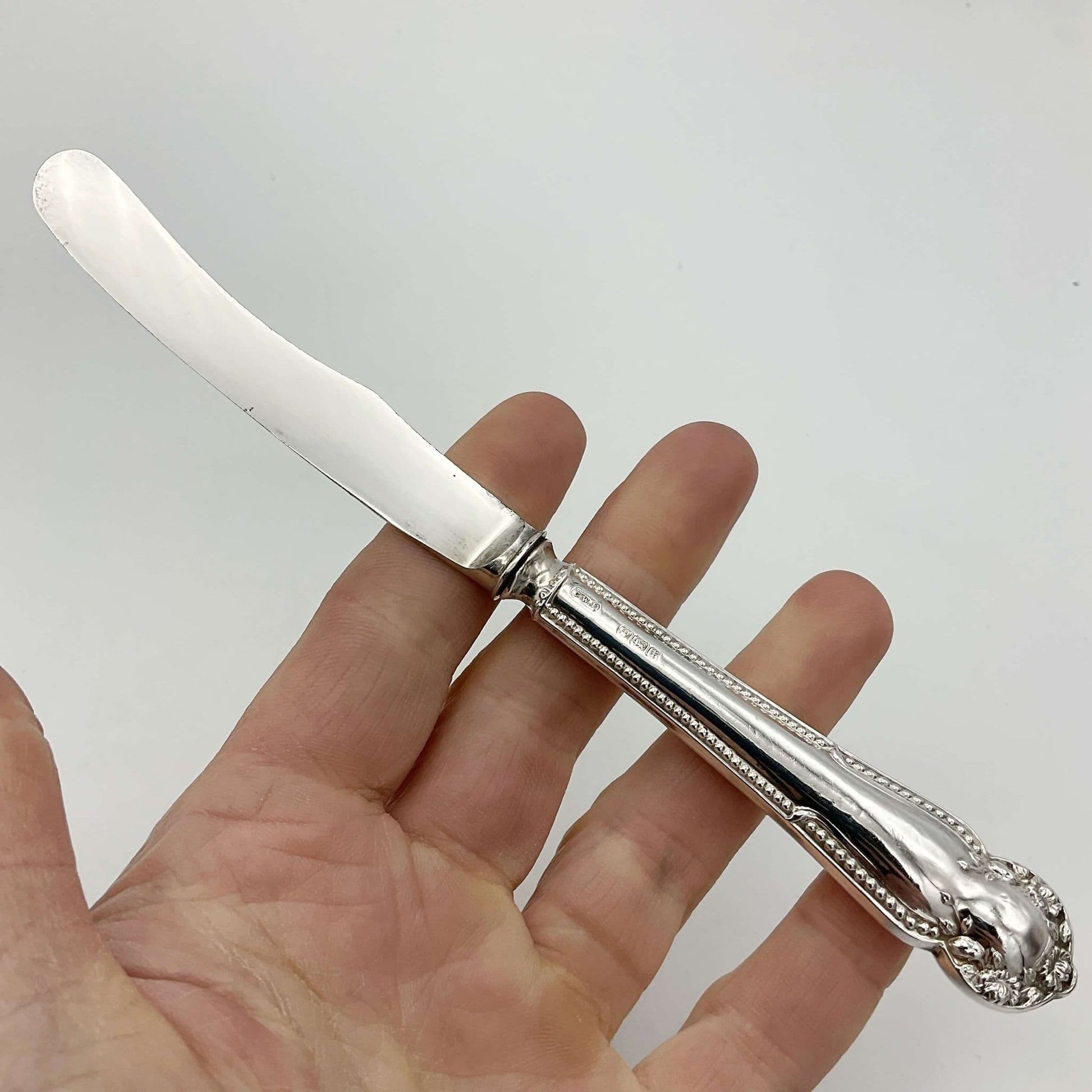 Antique silver side knife held in a hand