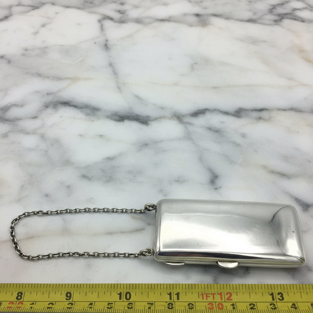 silver case and chain against a tape measure on a marble background