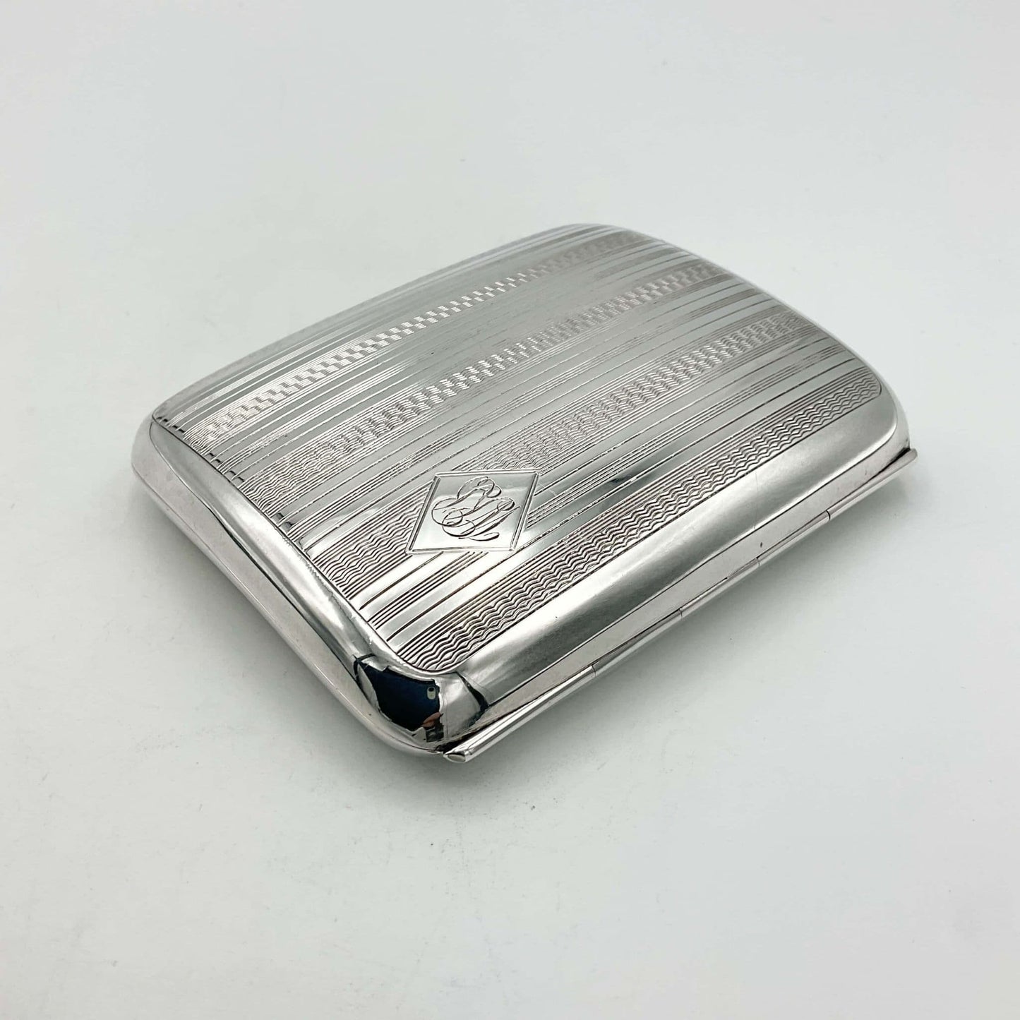 Antique 1920s silver cigarette case viewed from the hinge on a white background