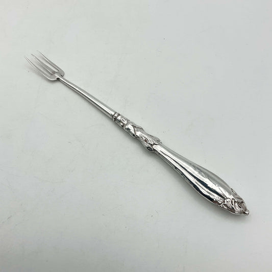 Antique silver plated pickle fork with an ornate handle on a plain background